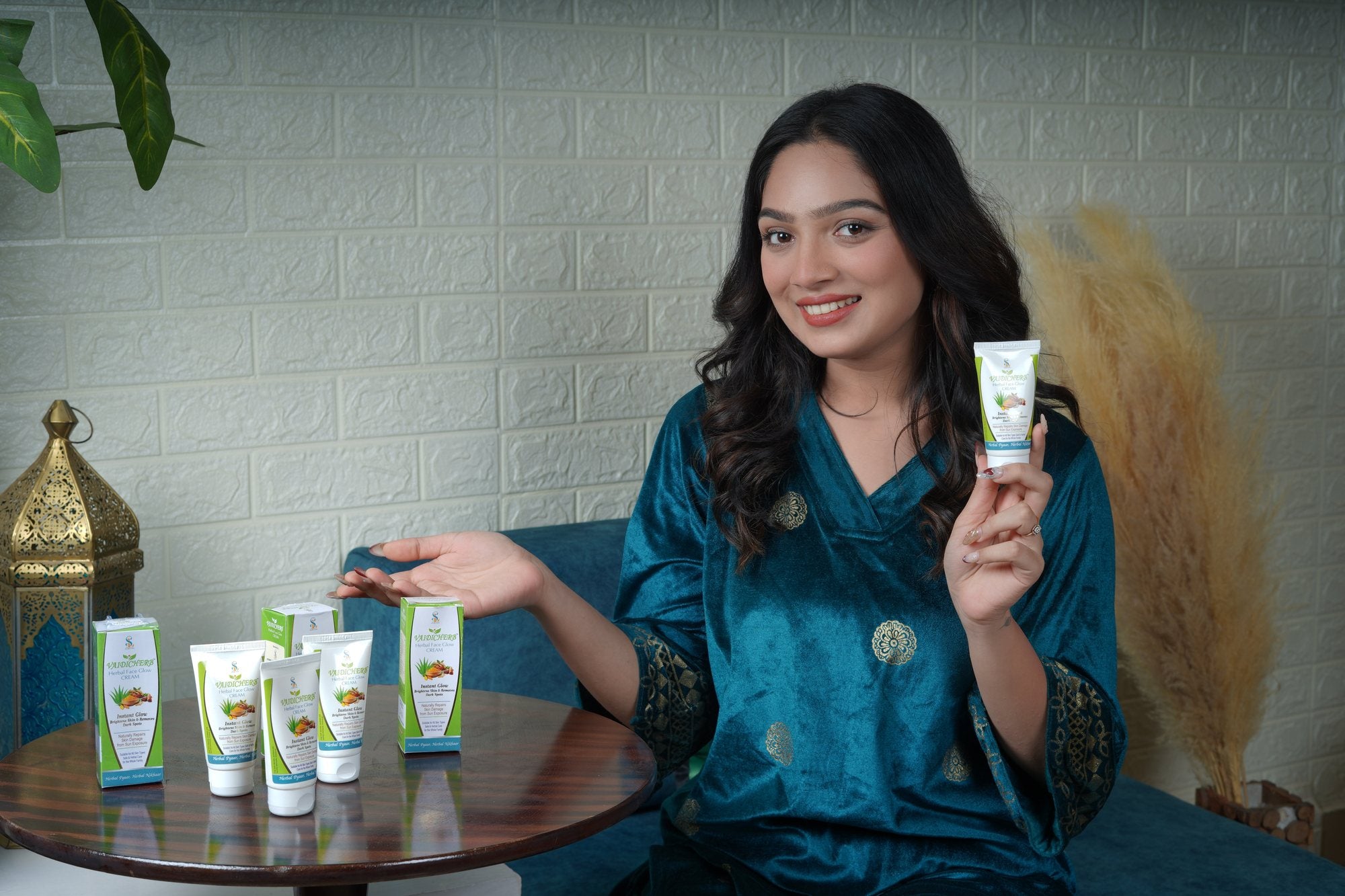 Smiling woman holding VaidicHerb Herbal Face Glow Cream with the product packs on a table